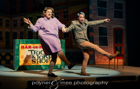 H25W-044 Two men (one dressed as a woman in housecoat) arm in arm and kicking a foot out in a chorus line dance style.